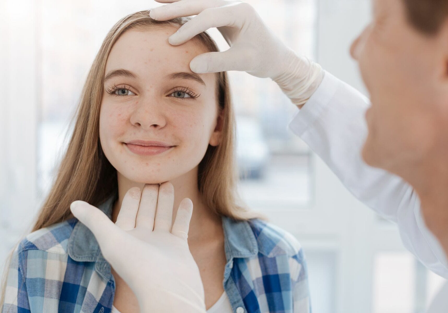 Friendly medical appointment . Qualified positive easygoing dermatologist enjoying working hours in the hospital and sitting in the cabinet while examining patient face